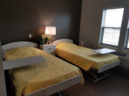 A cozy bedroom featuring two twin beds with yellow bedding, a bedside lamp, and a window allowing natural light.