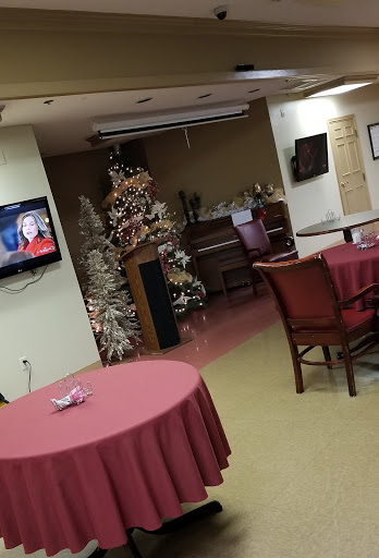 A cozy restaurant interior decorated for the holiday season, featuring a Christmas tree and a television.