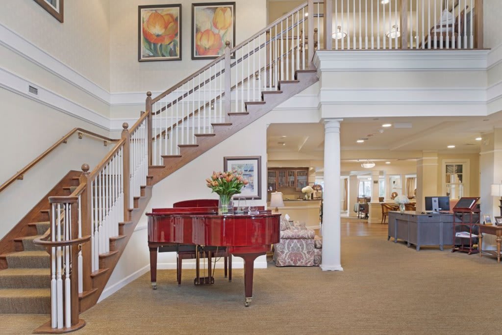 A spacious living room featuring a grand piano and elegant staircase.