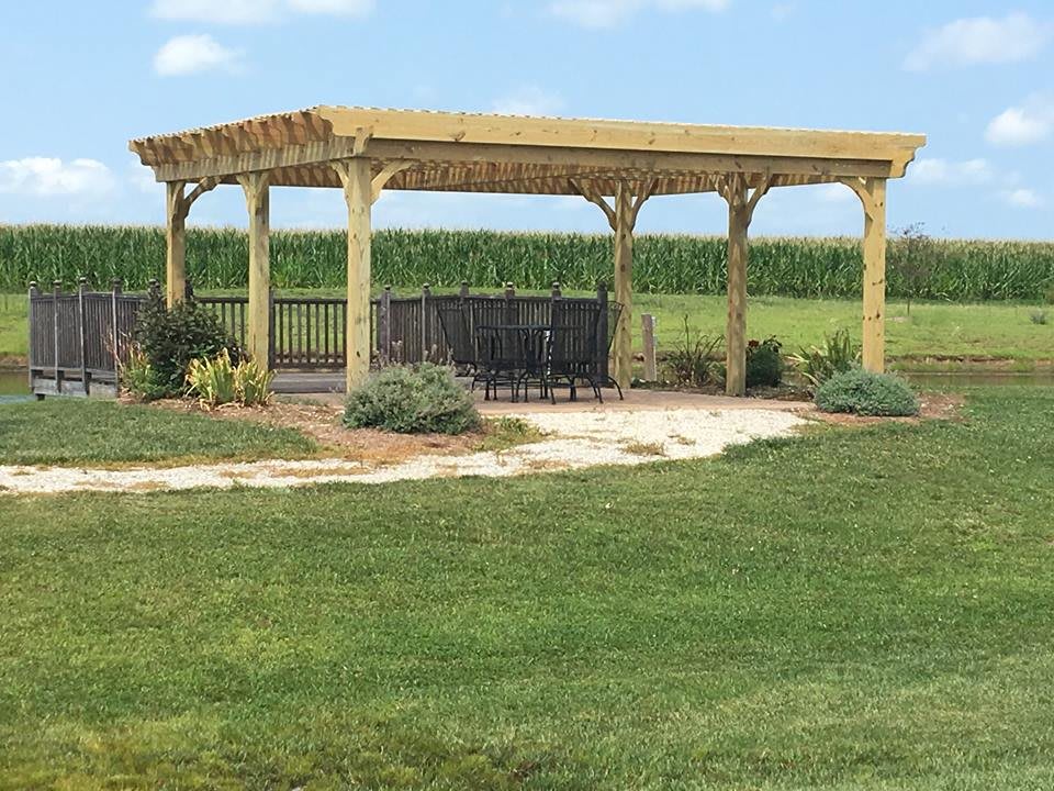 A wooden gazebo in a scenic garden landscape.
