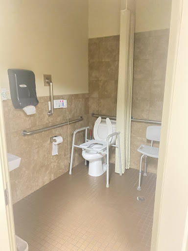 An accessible restroom equipped with support bars and a chair.