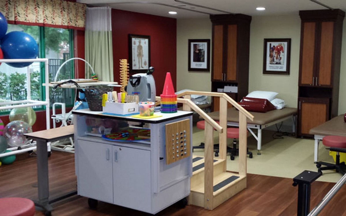 A rehabilitation room equipped with therapy equipment and furniture.