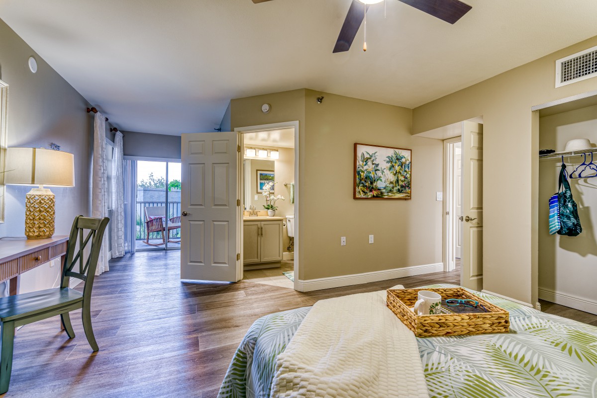 A modern bedroom with elegant decor, featuring wood flooring and ample natural light.