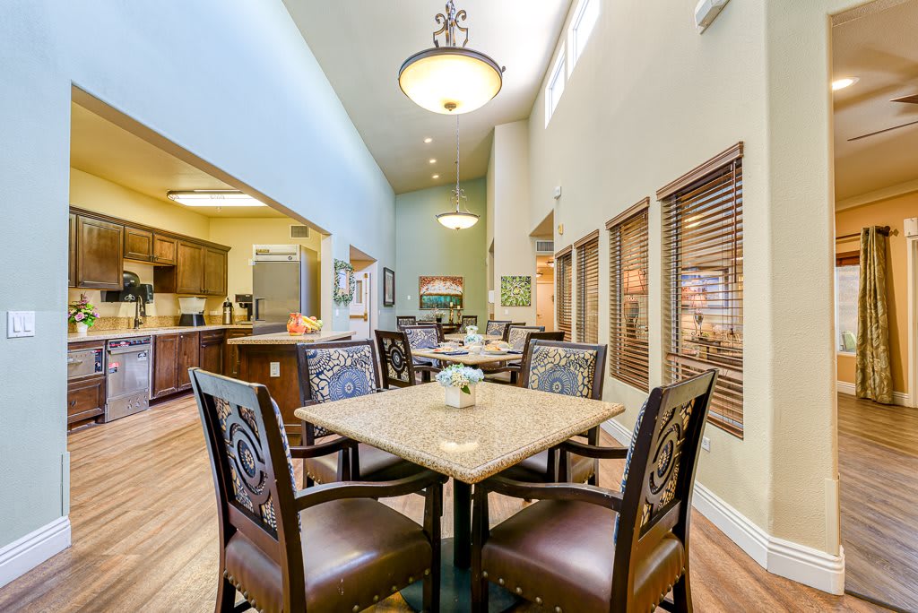 A cozy dining area with elegant furniture and warm lighting, adjacent to a modern kitchen.