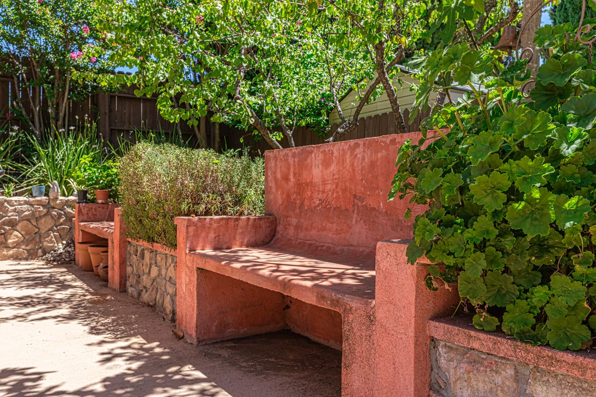 A sunny garden scene with a rustic pink bench surrounded by lush greenery.