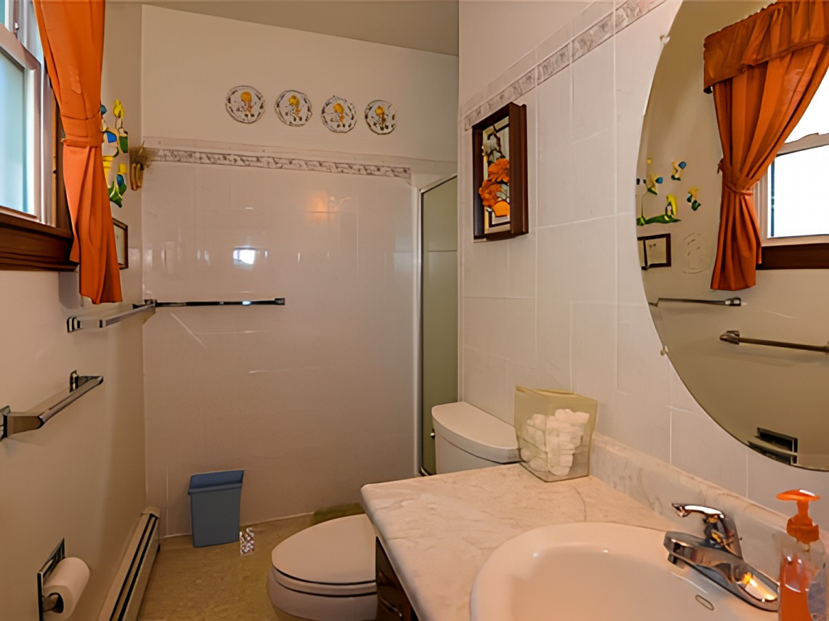 A clean and well-organized bathroom with a sink, mirror, toilet, and walk-in shower.