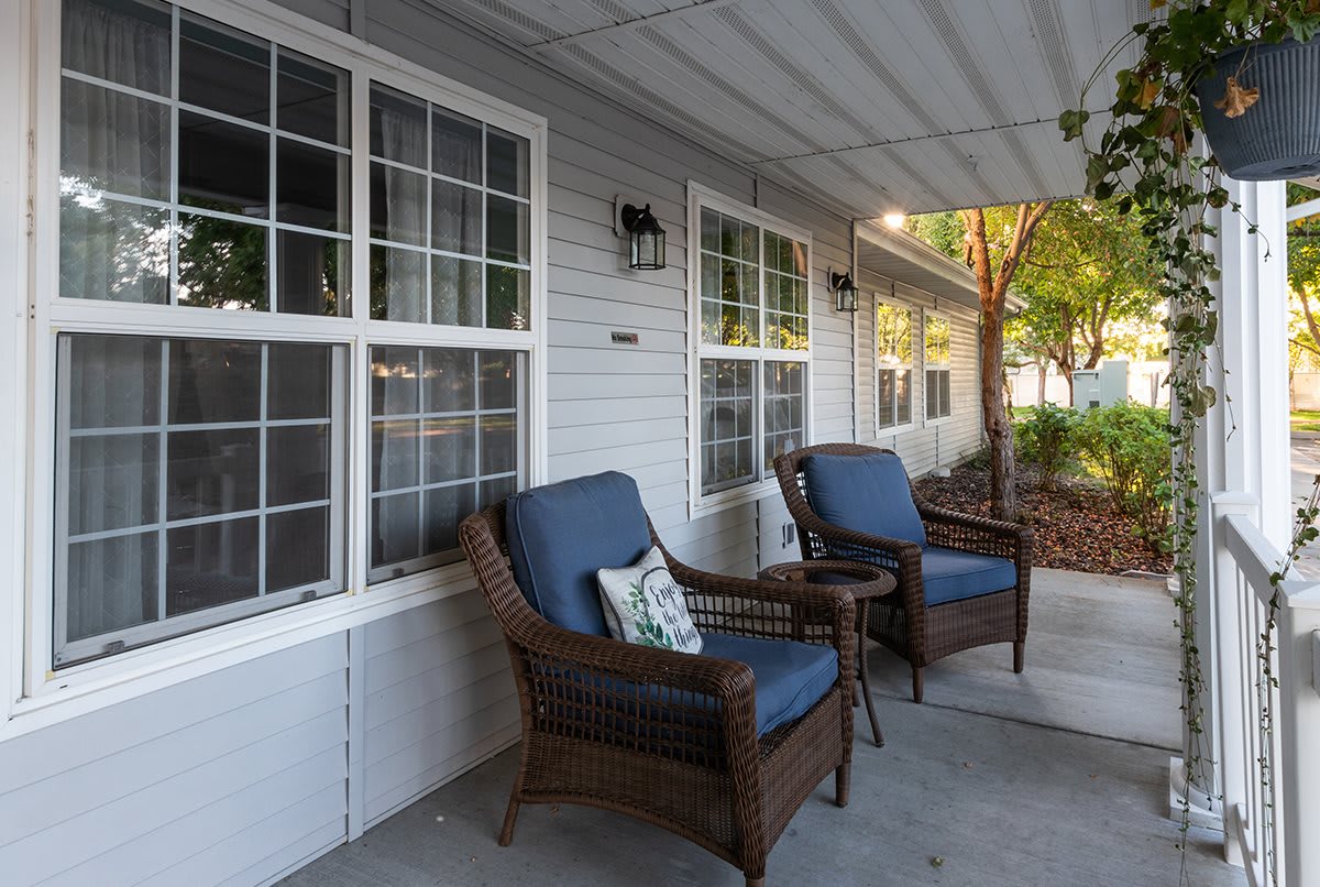 A cozy outdoor patio with wicker chairs and cushions, ideal for relaxing on a pleasant evening.