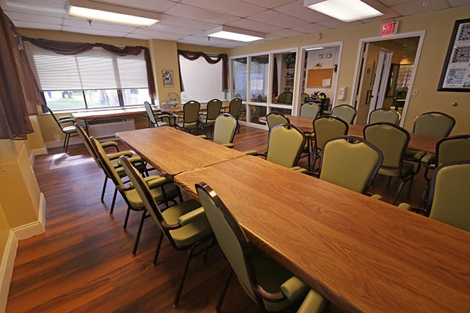 A modern conference room with a long table surrounded by chairs and large windows.