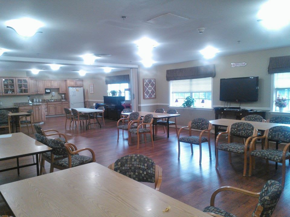A community room with chairs, tables, and a television.