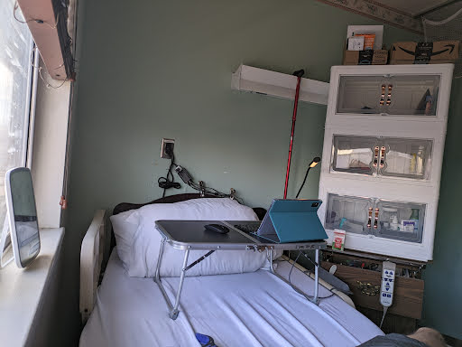 A hospital room featuring a bed with a laptop table set up beside it.