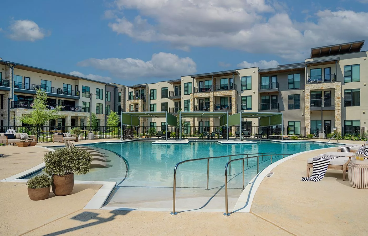 A modern apartment complex with a large outdoor swimming pool.