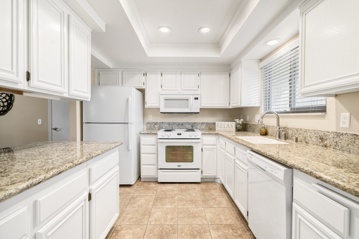 A bright kitchen with white cabinets and modern appliances.