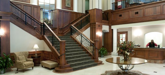 An elegant lobby featuring a grand staircase with wood paneling and classic interior design.
