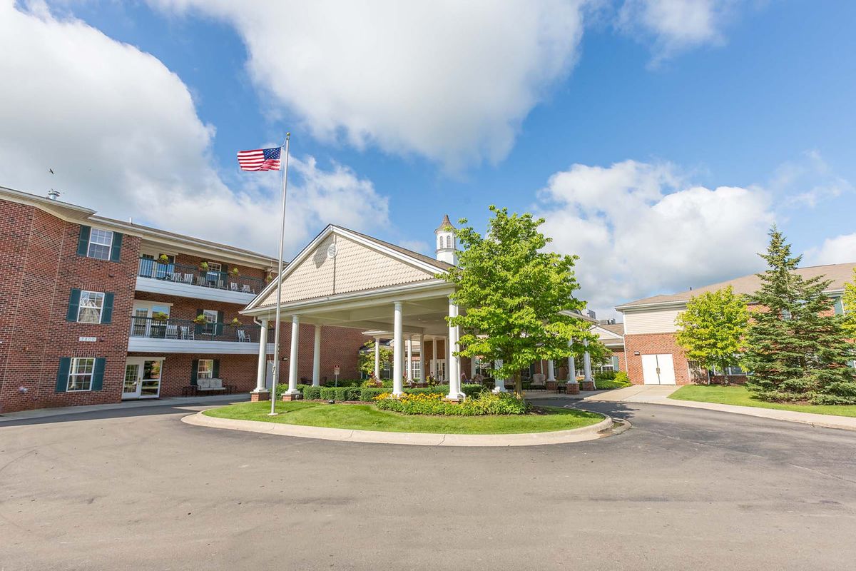 A hotel entrance with an American flag flying under a partly cloudy sky.
