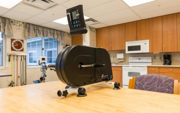 A pedal exerciser placed on a table in a kitchen-like setting, commonly used for rehabilitation and fitness.