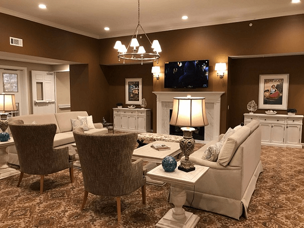 A cozy, elegantly decorated living room featuring comfortable seating, a chandelier, and a warm fireplace.