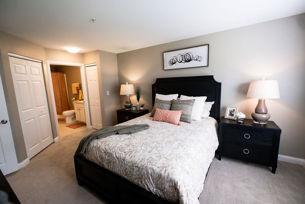 A modern and cozy bedroom with a neatly made bed, nightstands, and warm lighting.