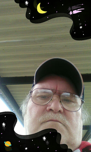 A man taking a selfie outdoors under a shelter.