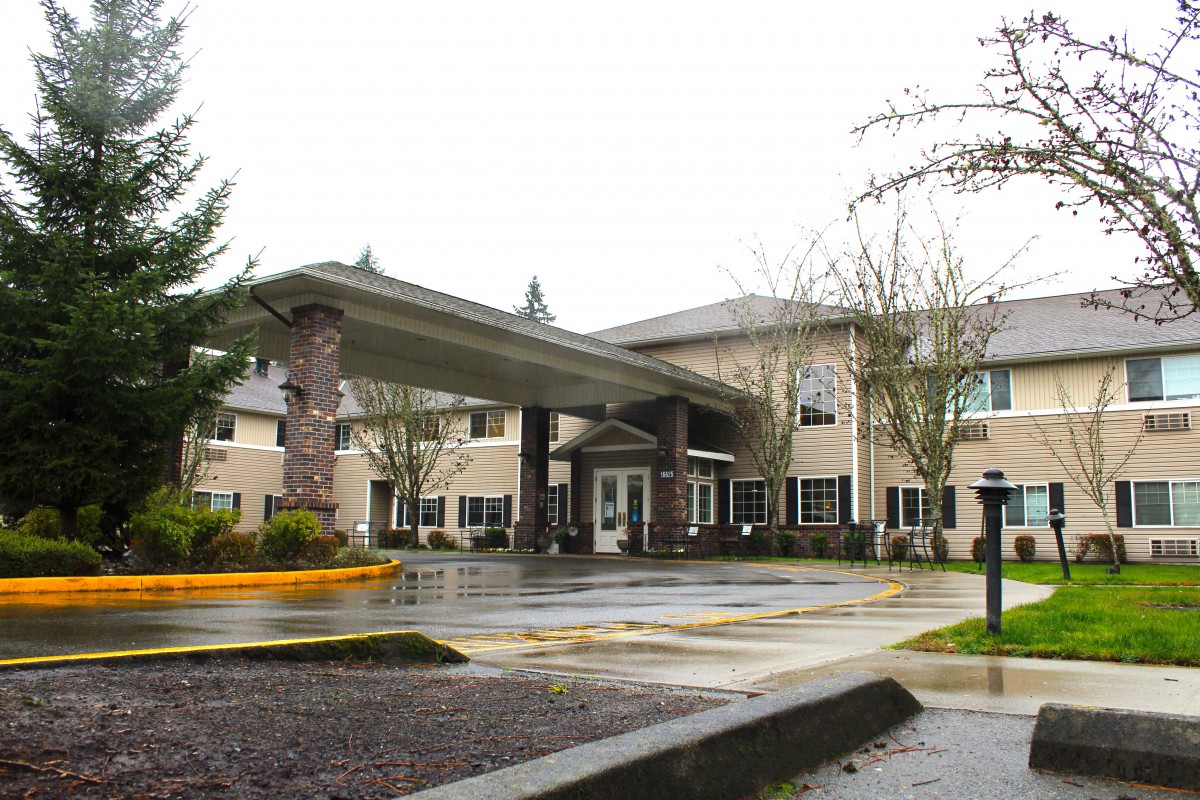 A large building with a covered entrance and surrounding trees on an overcast day.
