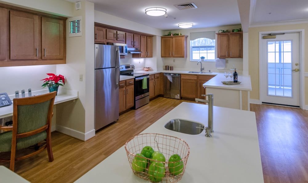 A modern kitchen with wooden cabinets, stainless steel appliances, and a fruit bowl on the countertop.