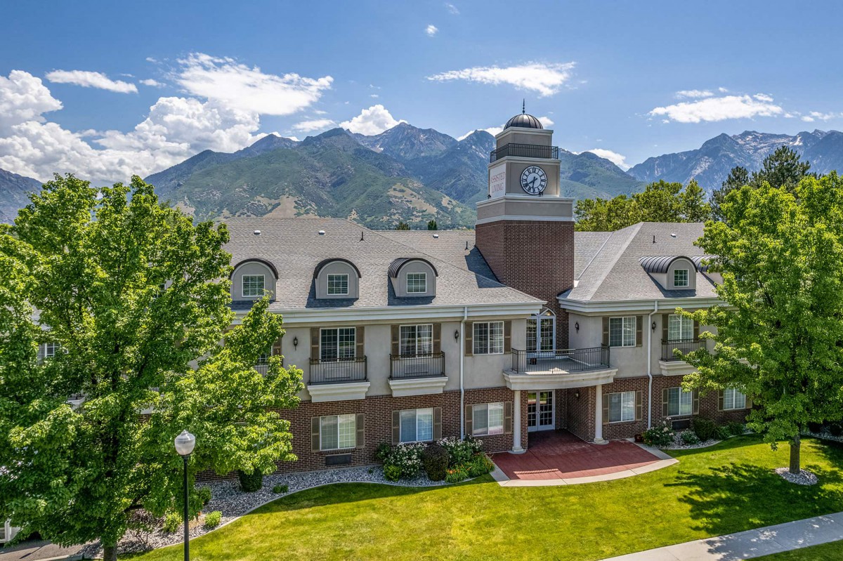 A picturesque building set against a backdrop of mountains with a bright sky and lush greenery.
