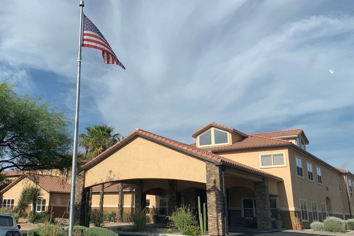 A building with an American flag in front and a cloudy sky above.