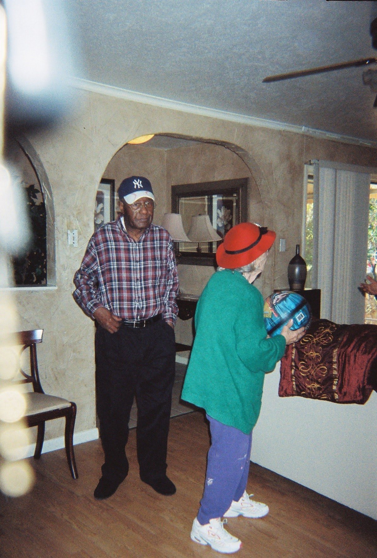 Two people wearing hats standing in a living room area.