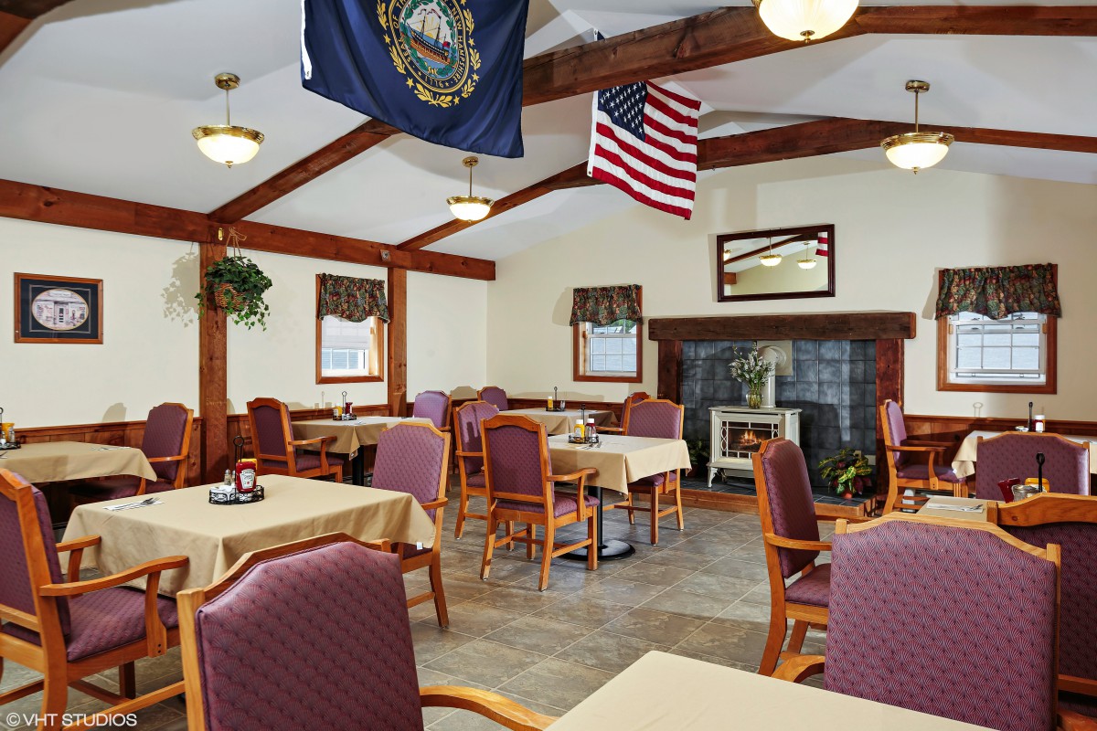 A cozy dining area with multiple tables and chairs, adorned with American and state flags.