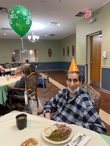 An elderly man enjoying a birthday celebration with a festive party hat and a cheerful atmosphere.