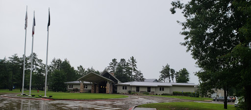 A modern building set in a rainy landscape, surrounded by trees.