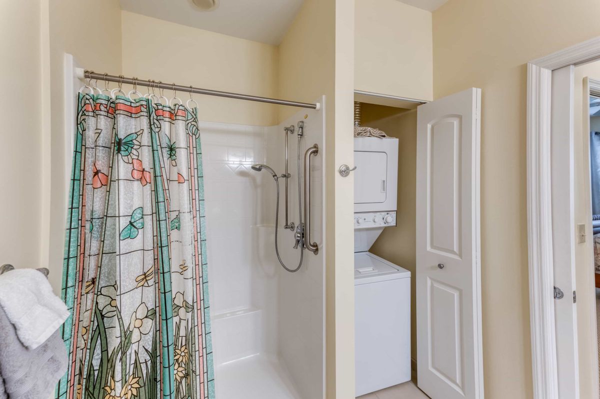 A compact bathroom with a shower and stacked washer-dryer unit.