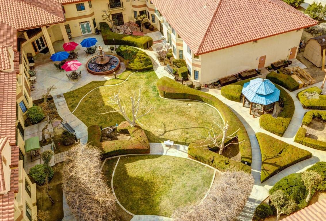 Aerial view of a landscaped courtyard with pathways, patio furniture, and colorful umbrellas.