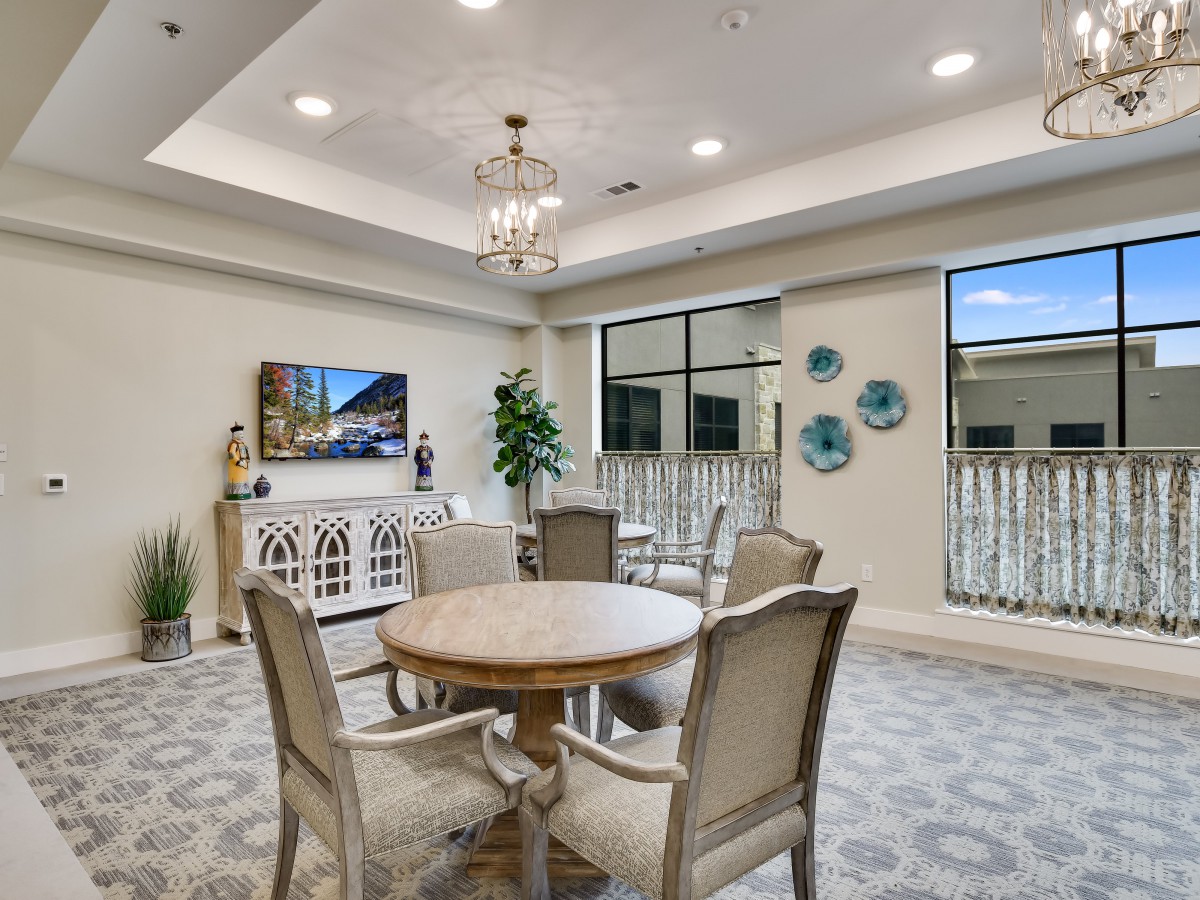 A stylish dining area with elegant decor and a round table, illuminated by a chandelier.