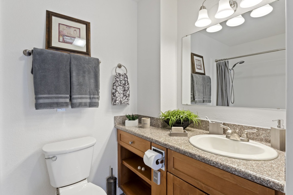 A clean and modern bathroom with a sink, mirror, and wooden cabinets.
