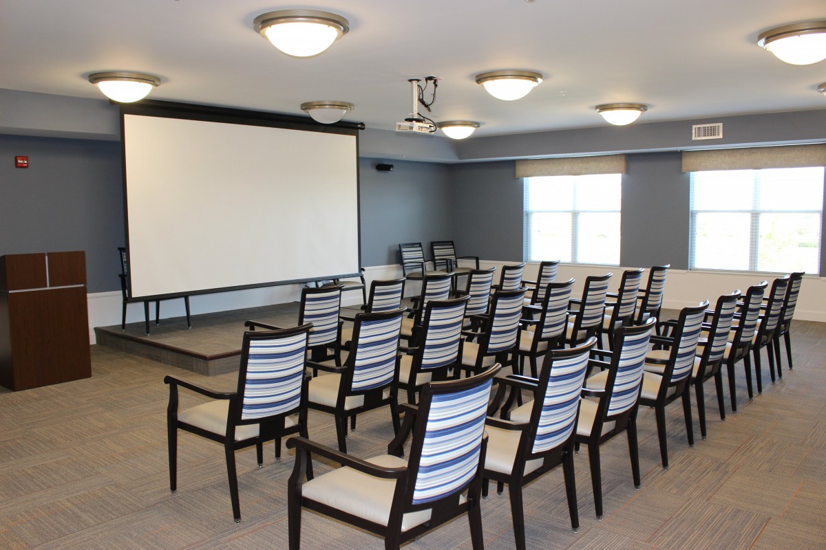 An empty conference room set up with chairs facing a projector screen.