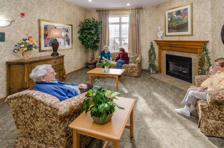 A cozy living room with seniors engaging in conversation by the fireplace.
