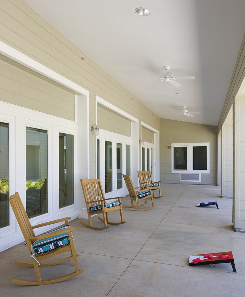 A spacious porch with several rocking chairs offers a serene outdoor seating area.