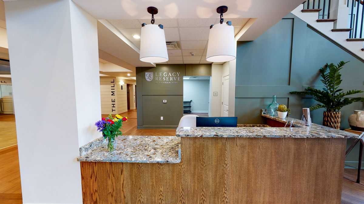 A welcoming reception area with a granite desk, decorative lighting, and a vase of flowers.