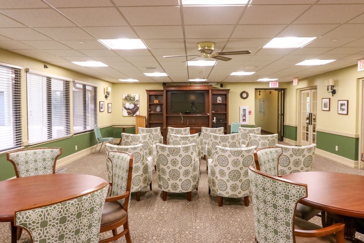A cozy seating area with patterned chairs arranged facing a television in a well-lit room.