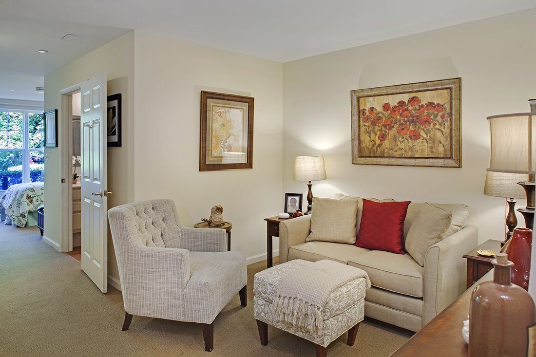 A cozy living room with a sofa, armchair, and wall art.