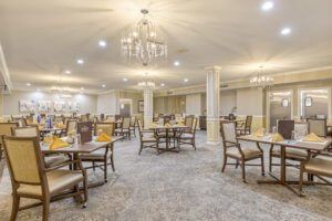 Elegant dining room with chandeliers and neatly arranged tables and chairs.