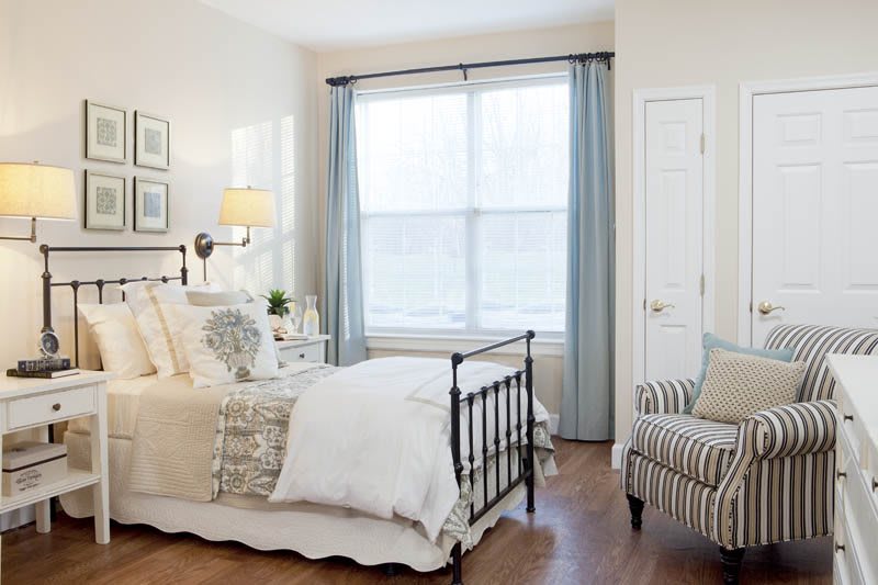 A cozy bedroom with a metal bed frame, soft lighting, and neutral color tones.