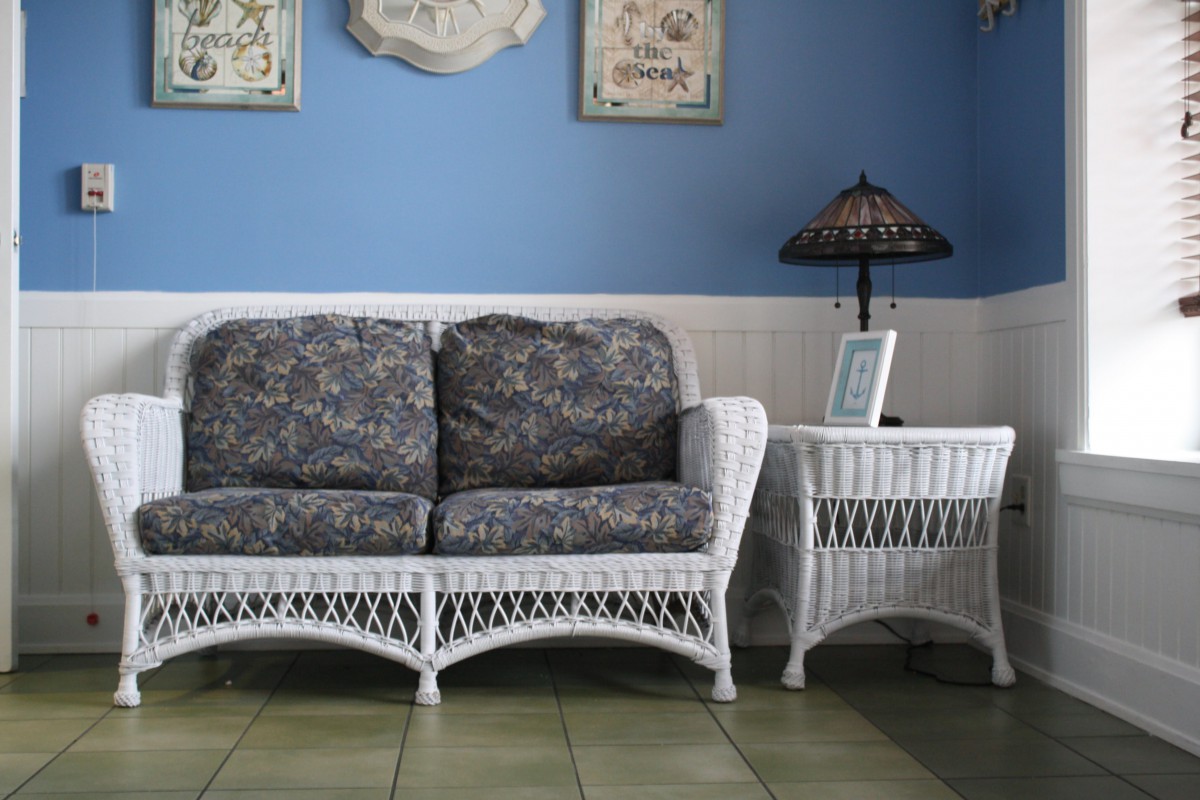 A cozy living room setup featuring a wicker sofa and side table against a blue wall.