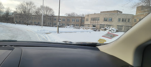 A view from inside a vehicle showing a snowy landscape in front of a school building.