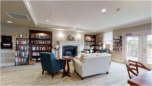 A cozy living room featuring comfortable seating, a fireplace, and shelves filled with books.