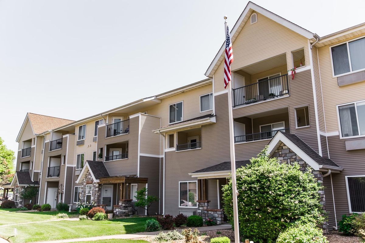A well-maintained apartment building with an American flag displayed in the front yard.