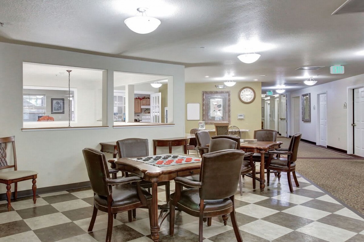 An empty dining area with tables and chairs arranged on a checkered floor.