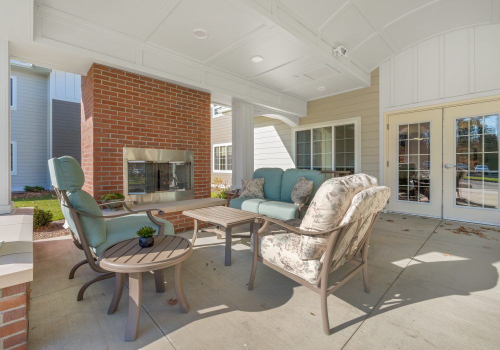 A cozy outdoor patio with comfortable seating and a brick fireplace.