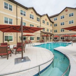 Outdoor pool area of a hotel with surrounding patio furniture and umbrellas.
