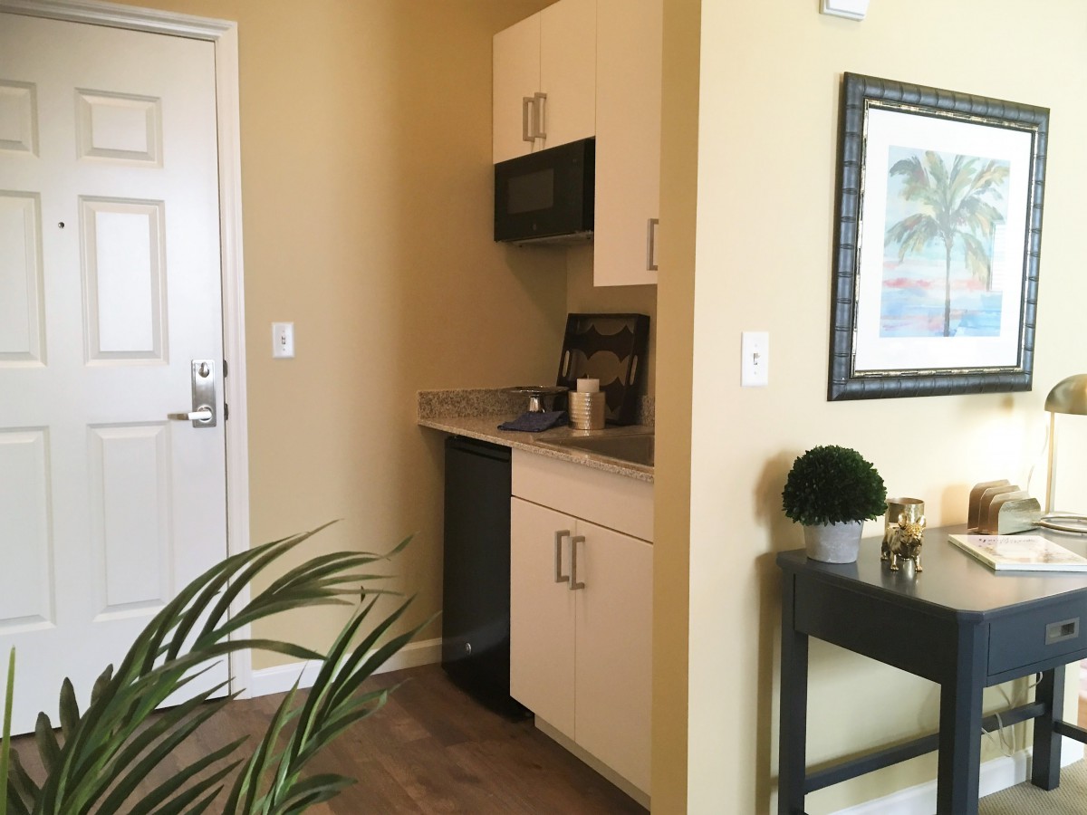 A modern kitchenette with cabinetry, microwave, and decorative elements.